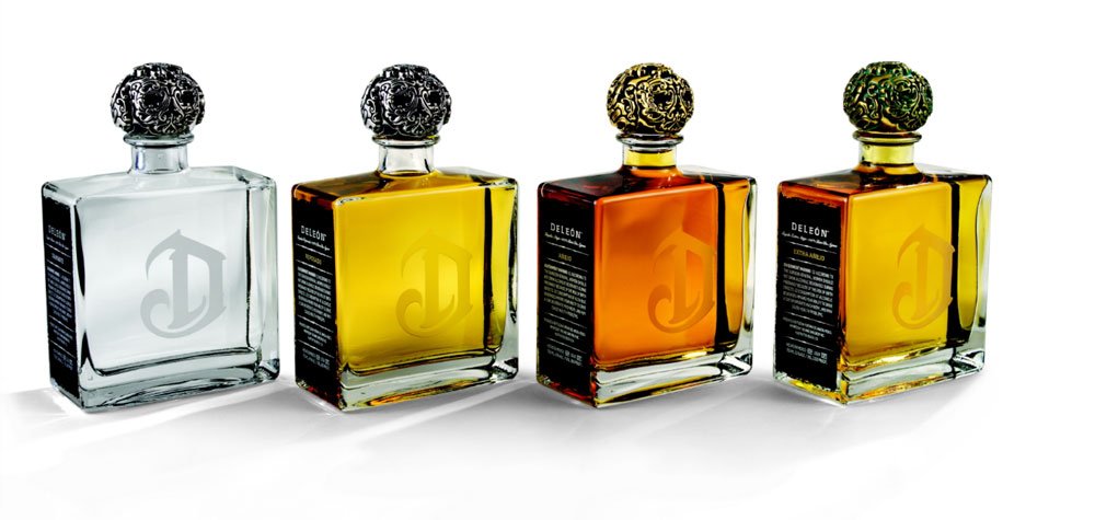 Three crystal decanters of premium DeLeón tequila on a white background